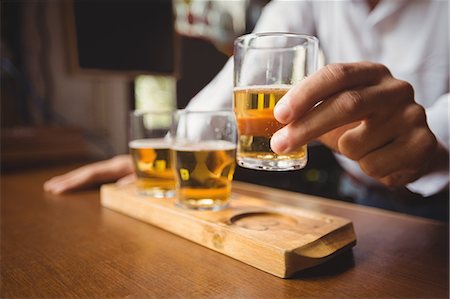 Close-up of bartender holding whisky shot glass at bar counter in bar Stock Photo - Premium Royalty-Free, Code: 6109-08782700