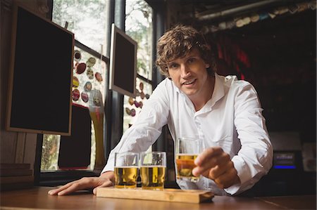 Portrait of bartender holding whisky shot glass at bar counter in bar Stock Photo - Premium Royalty-Free, Code: 6109-08782701