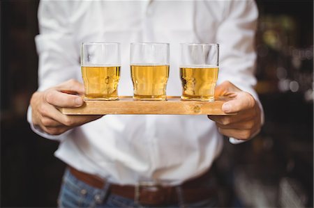 Mid section of bartender holding tray of whisky shot glasses at bar counter in bar Stock Photo - Premium Royalty-Free, Code: 6109-08782707