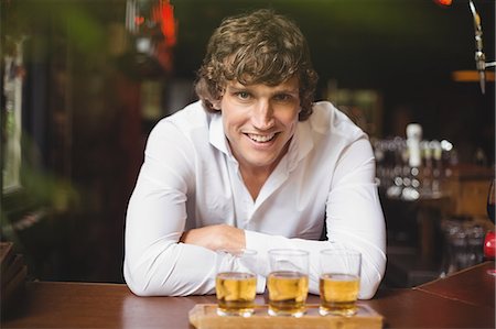 Portrait of bartender with tray of whisky shot glasses at bar counter in bar Stock Photo - Premium Royalty-Free, Code: 6109-08782708