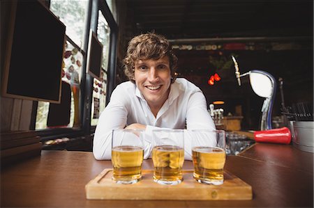 Portrait of bartender with tray of whisky shot glasses at bar counter in bar Stock Photo - Premium Royalty-Free, Code: 6109-08782709