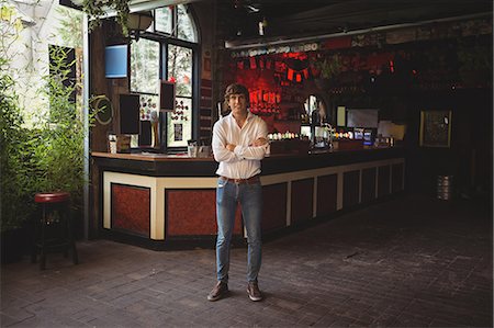 Portrait of smiling man standing with arms crossed in bar Stock Photo - Premium Royalty-Free, Code: 6109-08782715