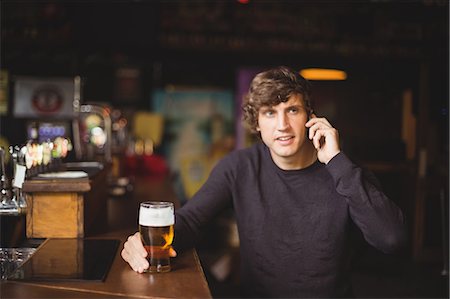 simsearch:6109-08782733,k - Man talking on mobile phone in bar with glass of beer in hand Stock Photo - Premium Royalty-Free, Code: 6109-08782731