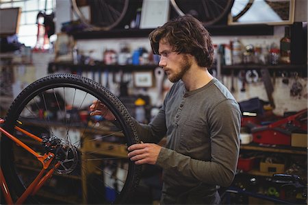 simsearch:6109-08782913,k - Mechanic examining a bicycle wheel in workshop Stock Photo - Premium Royalty-Free, Code: 6109-08782889