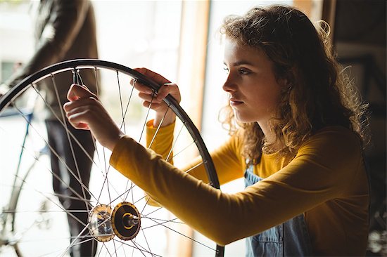 Mechanic examining a bicycle wheel in workshop Stock Photo - Premium Royalty-Free, Image code: 6109-08782898