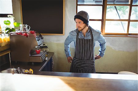 simsearch:6109-08829857,k - Waiter tying his apron in Café at bicycle shop Foto de stock - Royalty Free Premium, Número: 6109-08782941