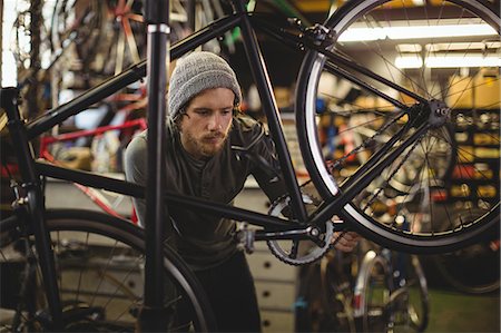 simsearch:6109-08782913,k - Mechanic examining a bicycle in bicycle workshop Stock Photo - Premium Royalty-Free, Code: 6109-08782902