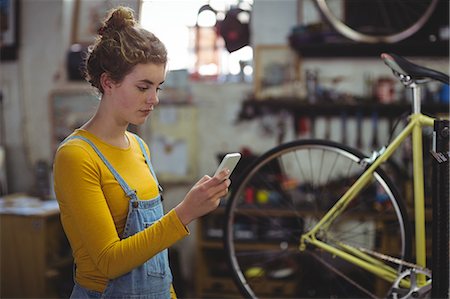 Mechanic using mobile phone in bicycle shop Stock Photo - Premium Royalty-Free, Code: 6109-08782907