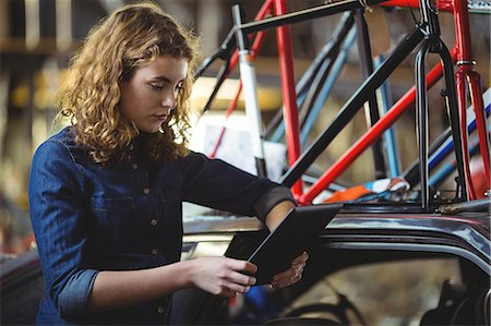 Mechanic using digital tablet while repairing bicycle in workshop Stock Photo - Premium Royalty-Free, Code: 6109-08783008