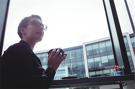 Young businesswoman holding coffee cup in cafe Stock Photo - Premium Royalty-Free, Code: 6109-08700455