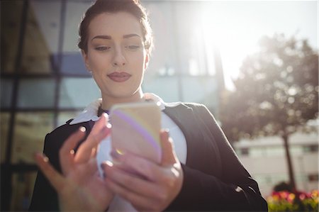 Young businesswoman using mobile phone on sunny day Stock Photo - Premium Royalty-Free, Code: 6109-08700456