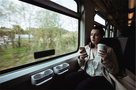 Young woman using mobile phone by window in train Photographie de stock - Premium Libres de Droits, Code: 6109-08700487