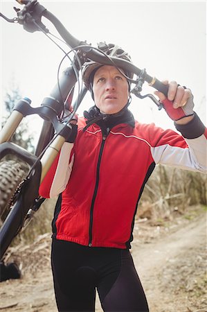 Front view of mountain biker carrying bicycle against sky Stock Photo - Premium Royalty-Free, Code: 6109-08700585