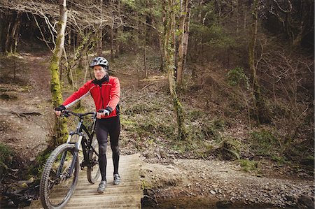 extreme sports and connect - Mountain biker walking with bicycle on footbridge in forest Stock Photo - Premium Royalty-Free, Code: 6109-08700593