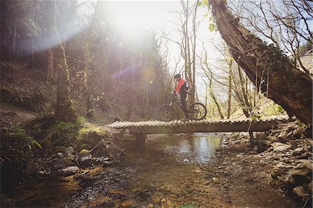 extreme sports and connect - Mountain biker on footbridge over stream in forest Stock Photo - Premium Royalty-Free, Code: 6109-08700591