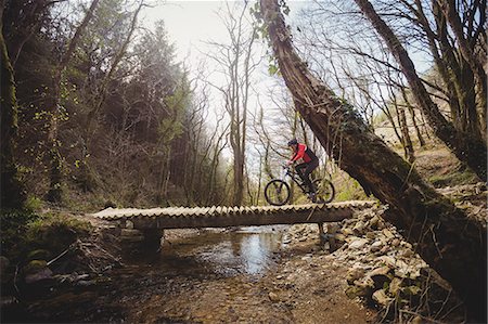extreme sports and connect - Mountain biker riding on footbridge over stream in forest Stock Photo - Premium Royalty-Free, Code: 6109-08700592
