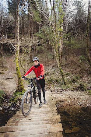 extreme sports and connect - Front view of mountain biker walking with bicycle on footbridge in forest Stock Photo - Premium Royalty-Free, Code: 6109-08700594