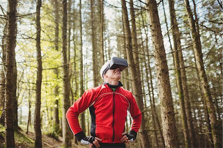 Man looking through virtual reality simulator amidst trees in forest Photographie de stock - Premium Libres de Droits, Code: 6109-08700522