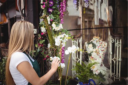 simsearch:6109-08700691,k - Female florist arranging flowers in vase at her flower shop Foto de stock - Sin royalties Premium, Código: 6109-08700688