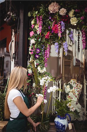 simsearch:6109-08700690,k - Female florist arranging flowers in vase at her flower shop Foto de stock - Sin royalties Premium, Código: 6109-08700689