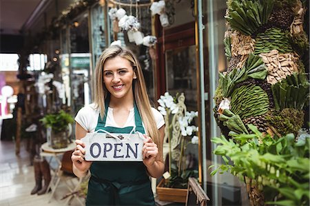 service store communication - Female florist holding open signboard outside the flower shop Stock Photo - Premium Royalty-Free, Code: 6109-08700633