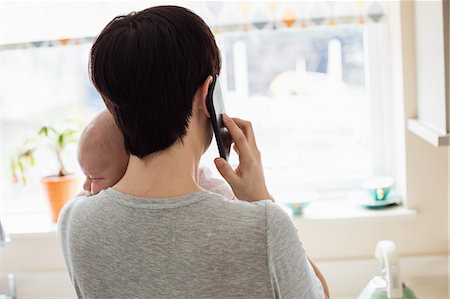 précieux - Mother holding her little baby while talking on phone in kitchen at home Photographie de stock - Premium Libres de Droits, Code: 6109-08700749