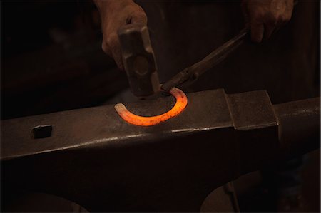 simsearch:6113-08424296,k - Hands of blacksmith working on a metal piece with hammer in workshop Photographie de stock - Premium Libres de Droits, Code: 6109-08700796