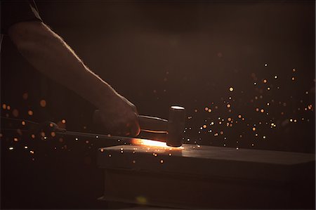 simsearch:6109-08700813,k - Hand of blacksmith working on iron rod with hammer in workshop Photographie de stock - Premium Libres de Droits, Code: 6109-08700798