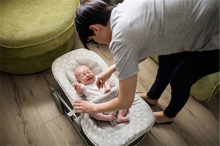 simsearch:6109-08700763,k - Mother consoling her crying baby in stroller in living room at home Stock Photo - Premium Royalty-Free, Code: 6109-08700737