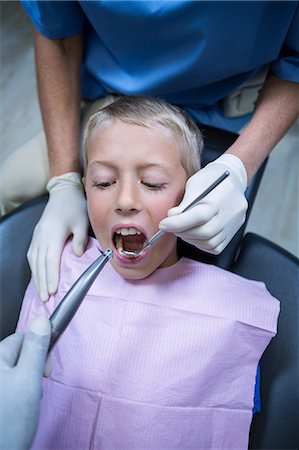 simsearch:6109-08700876,k - Dentist examining a young patient with tools at dental clinic Foto de stock - Royalty Free Premium, Número: 6109-08700845
