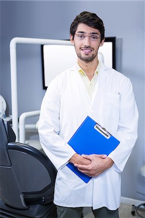 Portrait of smiling dentist standing with a clipboard at dental clinic Stock Photo - Premium Royalty-Free, Code: 6109-08700865