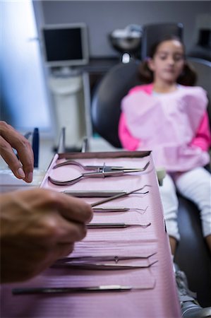 dentistry tray - Dentist picking up dental tools to examine a young patient at the clinic Stock Photo - Premium Royalty-Free, Code: 6109-08700883