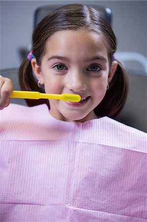 simsearch:6109-08700876,k - Portrait of young patient brushing her teeth at dentists clinic Foto de stock - Royalty Free Premium, Número: 6109-08700882