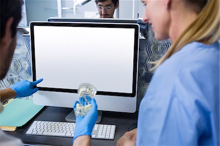 Dentist and dental assistant using a computer while working on mouth model Stock Photo - Premium Royalty-Free, Code: 6109-08700903