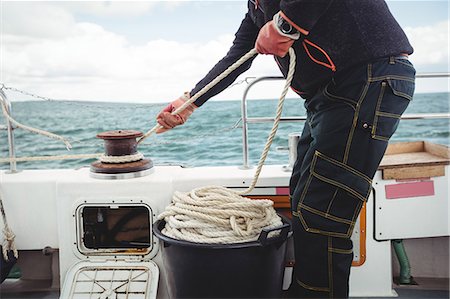 simsearch:6109-08701033,k - Fisherman tying rope on bollard in boat Photographie de stock - Premium Libres de Droits, Code: 6109-08701051