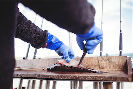 fish table knife - Close-up of fisherman filleting fish in boat Photographie de stock - Premium Libres de Droits, Code: 6109-08701062