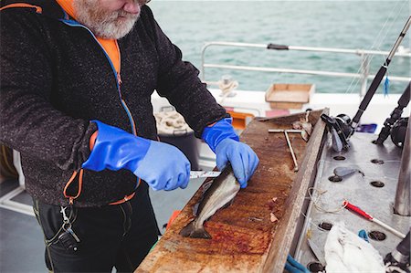 simsearch:6109-08701092,k - Fisherman filleting fish in boat Photographie de stock - Premium Libres de Droits, Code: 6109-08701067