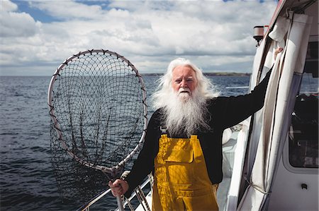 simsearch:6109-08701092,k - Portrait of fisherman holding fishing net on boat Photographie de stock - Premium Libres de Droits, Code: 6109-08701074