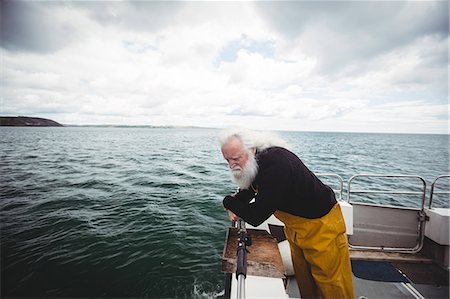simsearch:6109-08701033,k - Fisherman looking into the sea from fishing boat Photographie de stock - Premium Libres de Droits, Code: 6109-08701086