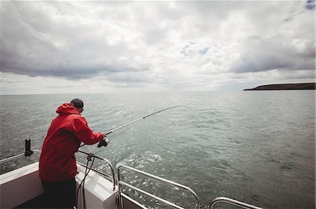 simsearch:6109-08701113,k - Fisherman fishing with fishing rod from the boat Stock Photo - Premium Royalty-Free, Code: 6109-08701093