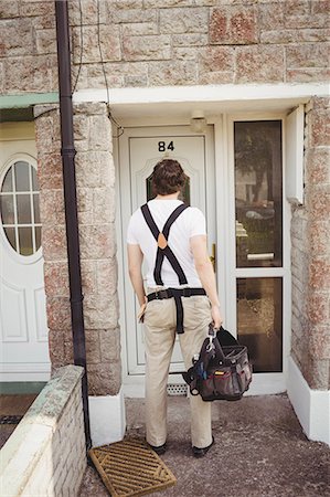 Carpenter standing with tool bag near house door Photographie de stock - Premium Libres de Droits, Code: 6109-08701018