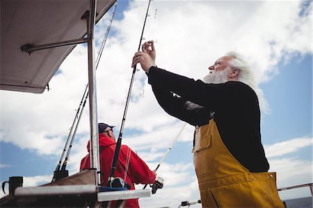 simsearch:6109-08701113,k - Fisherman preparing fishing rod on fishing boat Stock Photo - Premium Royalty-Free, Code: 6109-08701022