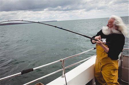 simsearch:6109-08701113,k - Fisherman fishing with fishing rod from the boat Stock Photo - Premium Royalty-Free, Code: 6109-08701103