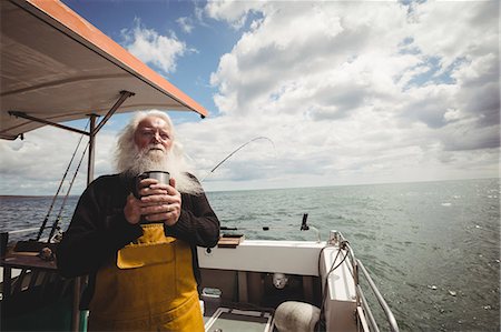 Thoughtful fisherman standing on boat with cup of coffee Stock Photo - Premium Royalty-Free, Code: 6109-08701109