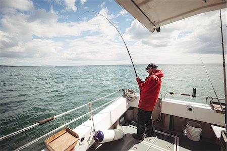 simsearch:6109-08701113,k - Fisherman fishing with fishing rod from the boat Stock Photo - Premium Royalty-Free, Code: 6109-08701110