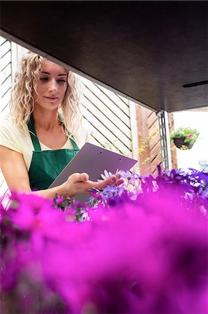 simsearch:6109-08701225,k - Female florist checking flowers in garden centre Stock Photo - Premium Royalty-Free, Code: 6109-08701217