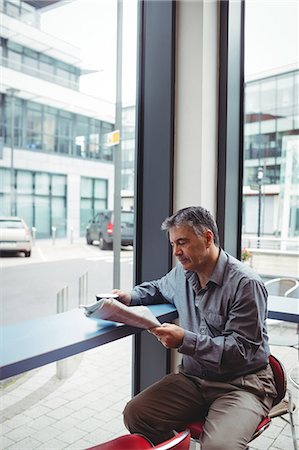 Man reading newspaper and holding coffee cup in cafeteria Stock Photo - Premium Royalty-Free, Code: 6109-08701347