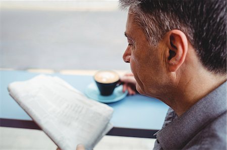periódico - Close-up of man reading newspaper and holding coffee cup in cafeteria Foto de stock - Sin royalties Premium, Código: 6109-08701354