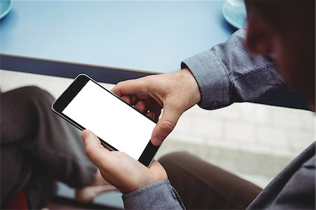 surfing the net - Close-up of man text messaging on mobile phone in cafeteria Photographie de stock - Premium Libres de Droits, Code: 6109-08701383