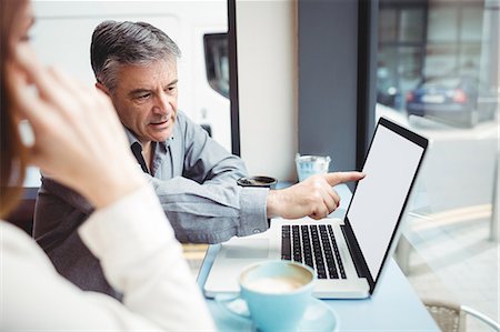 Man and woman discussing over laptop in the cafeteria Stock Photo - Premium Royalty-Free, Code: 6109-08701388